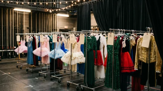 Organisation professionnelle des costumes de spectacle en coulisses avec portants étiquetés et système de rangement efficace